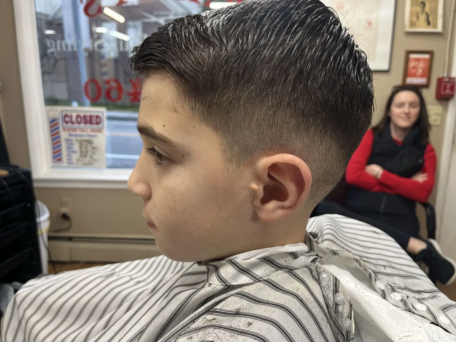 A boy with his hair slicked back and a low fade around the ear